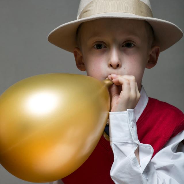 mladý muž nafukuje balónek